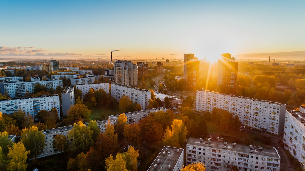 Mastering the First Impression: Your intriguing post title goes here Aerial view of a cityscape at sunrise with autumn foliage and modern buildings.