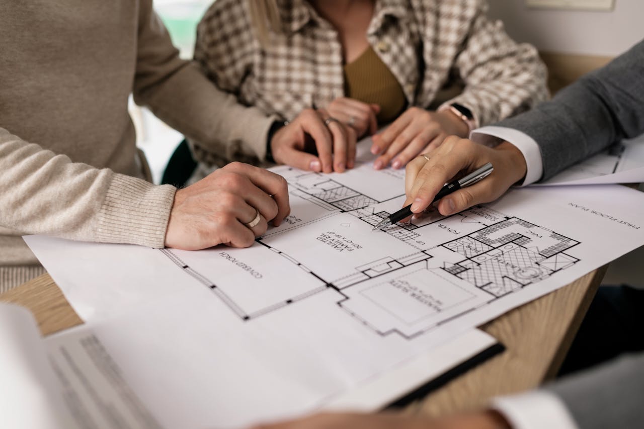 Crafting Captivating Headlines: Your awesome post title goes here Group examining house floor plans with a real estate agent, highlighting home buying process.